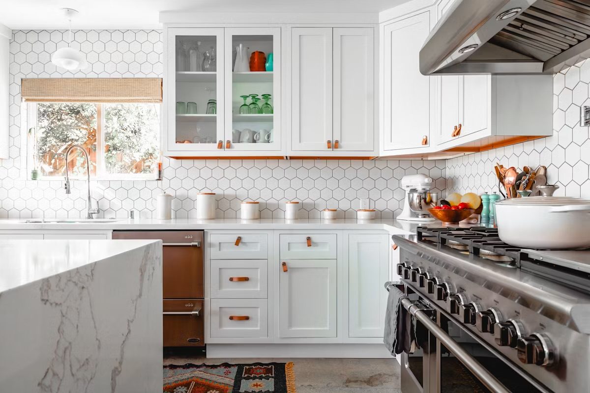 A white kitchen with hexagon tile and glass cabinets